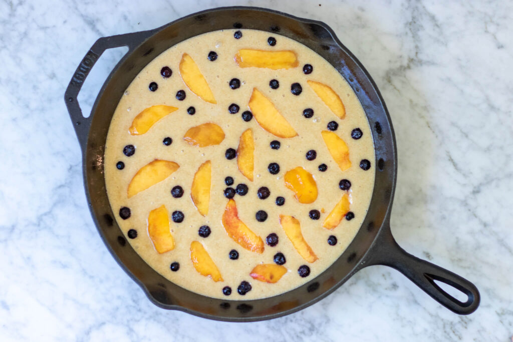 cobbler cake ingredients spread in a cast iron pan