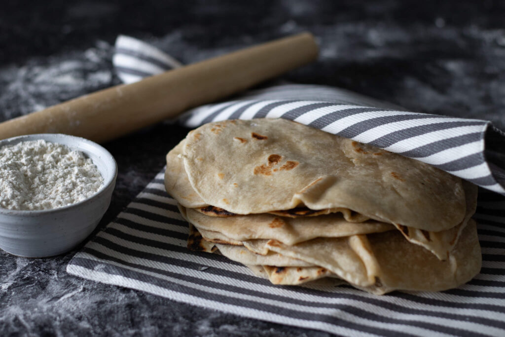 lard tortillas with flour in a bowl and a rolling pin