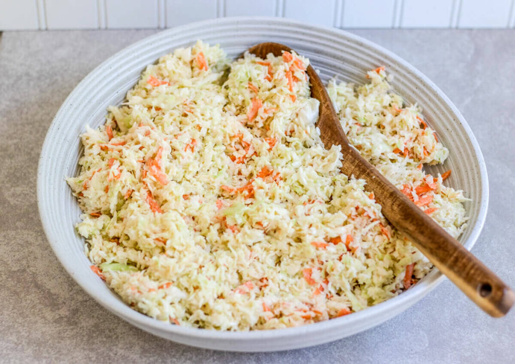 creamy cabbage in a bowl with a wooden spoon