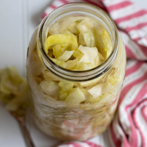 sauerkraut in a glass jar with a tea towel and fork