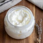 tallow balm on a wooden surface with a piece of dried lavender