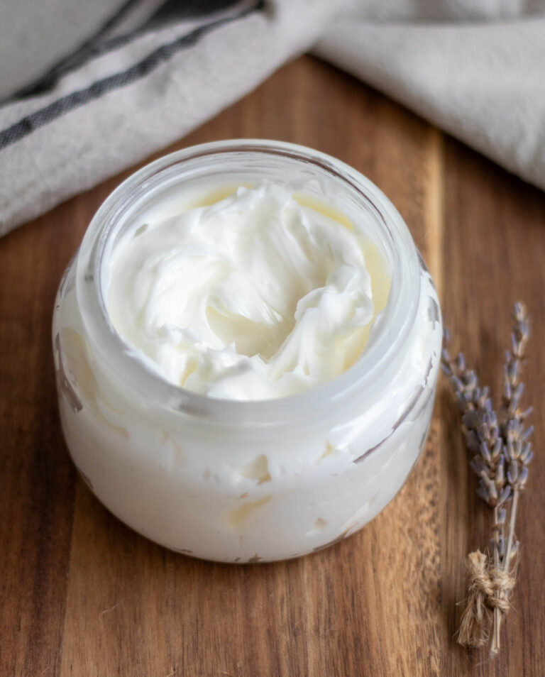 tallow balm on a wooden surface with a piece of dried lavender