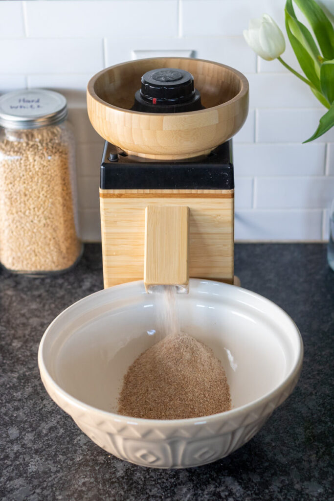 a grain mill milling flour into a bowl